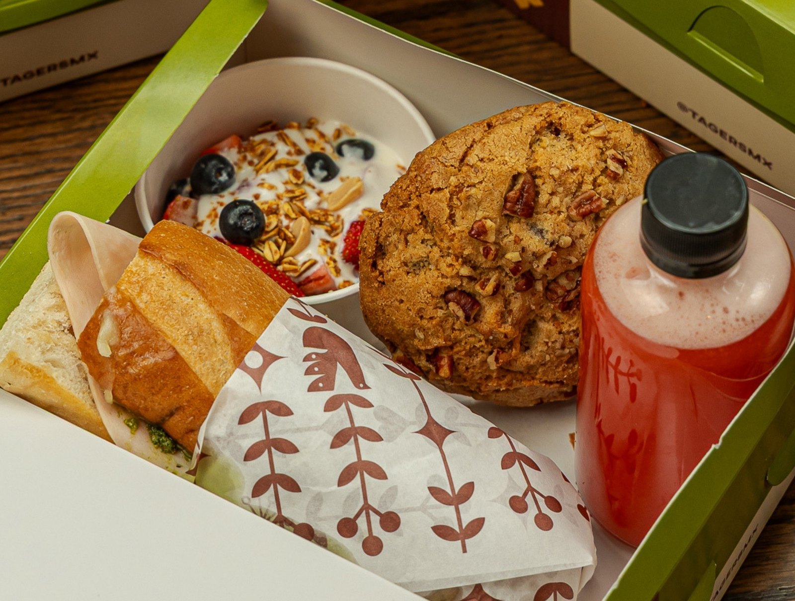 Caja de lunch corporativo de Tagers abierta: baguette envuelto, galleta, fruta con yogur y agua fresca