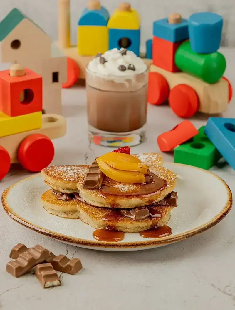 Kinder hot cakes Jr. con fruta y chocolate Kinder, un chocolate kids con crema batida y juguetes de madera