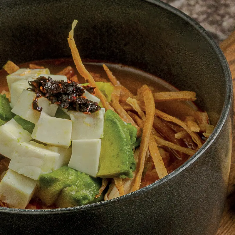 Caldo tlalpeño with chicken, avocado, panela cheese and tortilla strips