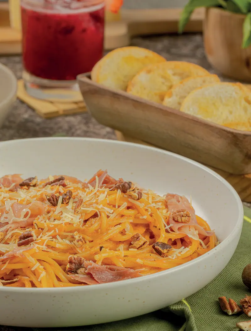Pasta jitomate y ajo rostizado con jamón serrano y nuez tostada, con pan de ajo al fondo