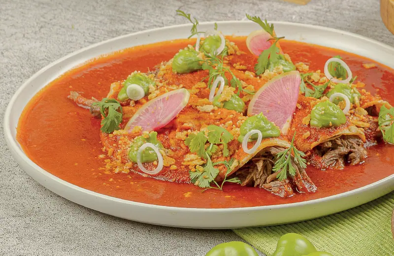 Enchiladas de barbacoa de picaña bañadas en adobo con rabanito sandía y cebollita