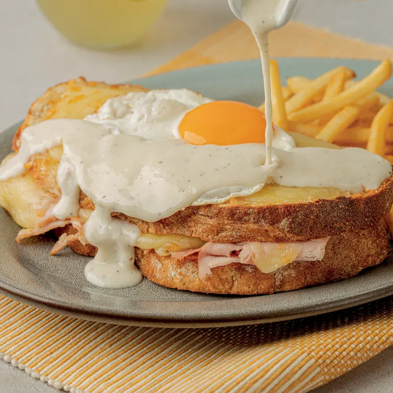 Croque madame with a fried egg and cheese sauce, with crispy fries