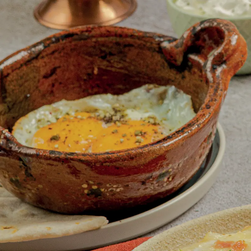 Eggs en cazuela in a clay pot with olive oil and za'atar
