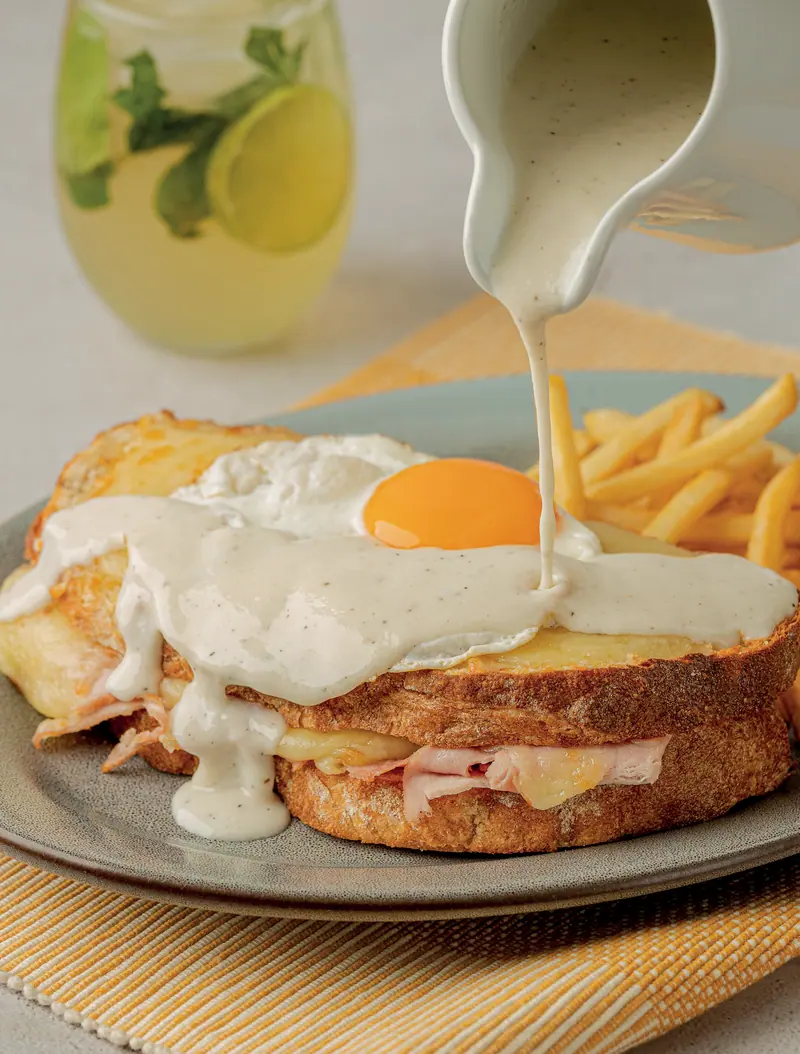 Croque madame with a fried egg and cheese sauce, with crispy fries