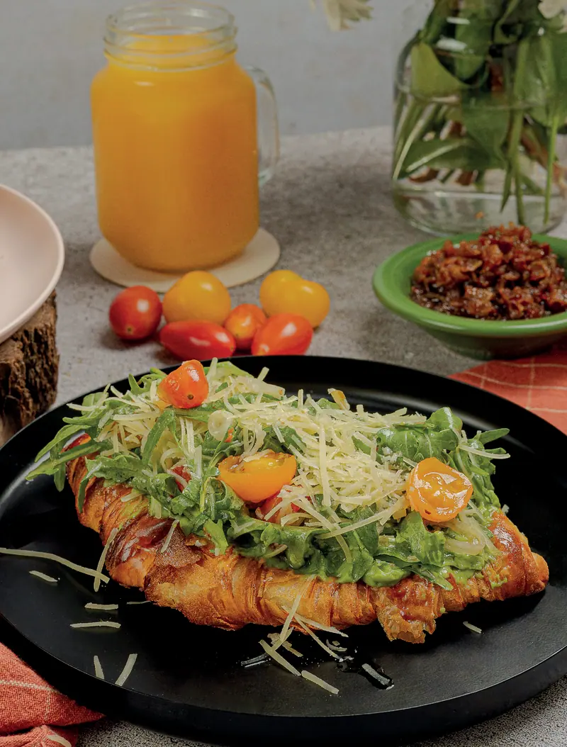 Croissant avo toast with poached egg, arugula and cherry tomatoes, with orange juice