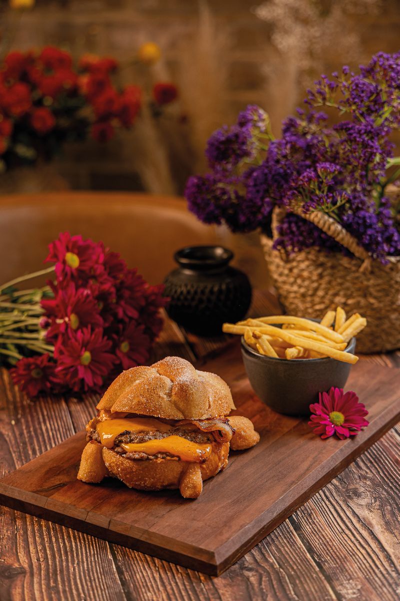 Catrina smash burger en pan de muerto azucarado, con queso cheddar y tocino, junto a un tazón de papas crispy