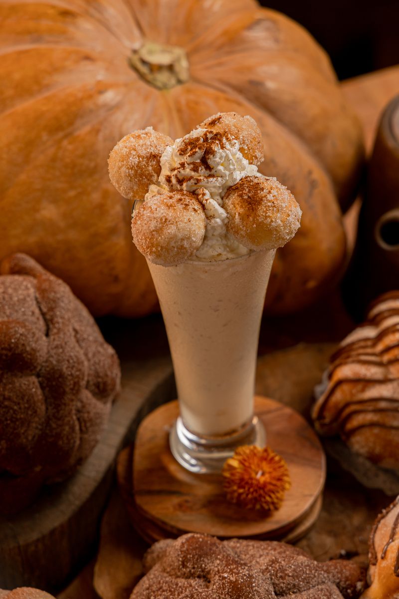 Malteada de pan de muerto coronada con un pan de muerto azucarado