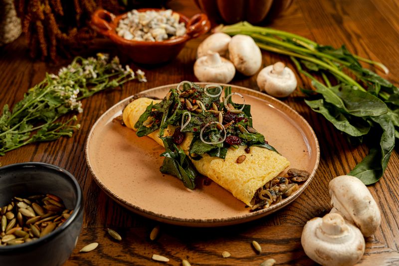 Omelette de hongos con ensalada de temporada, rodeado de champiñones frescos