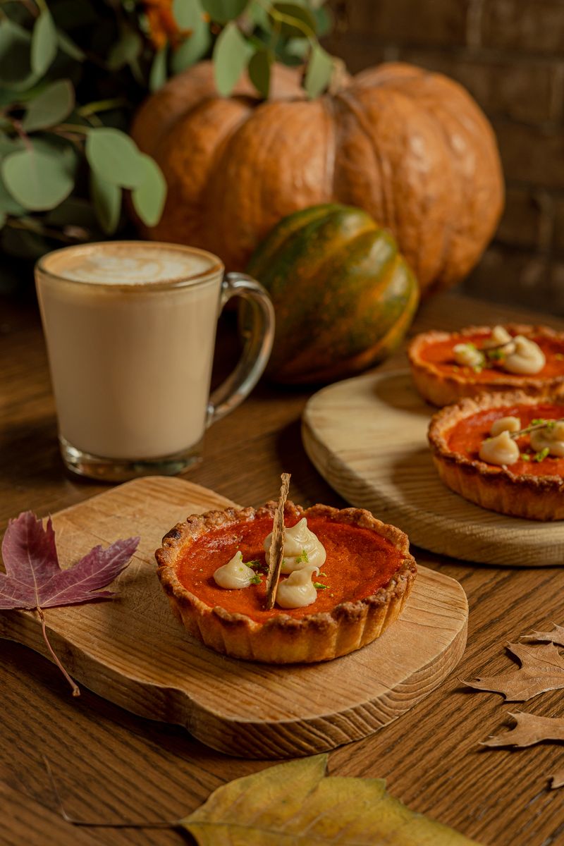 Pay de calabaza individual con nuez y glaseado, junto a un latte