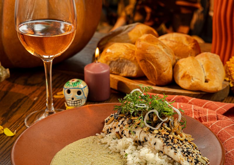 Una mesa de Tagers en otoño: copa de vino rosado, vela encendida, pan recién horneado y el pescado al pipián de la temporada