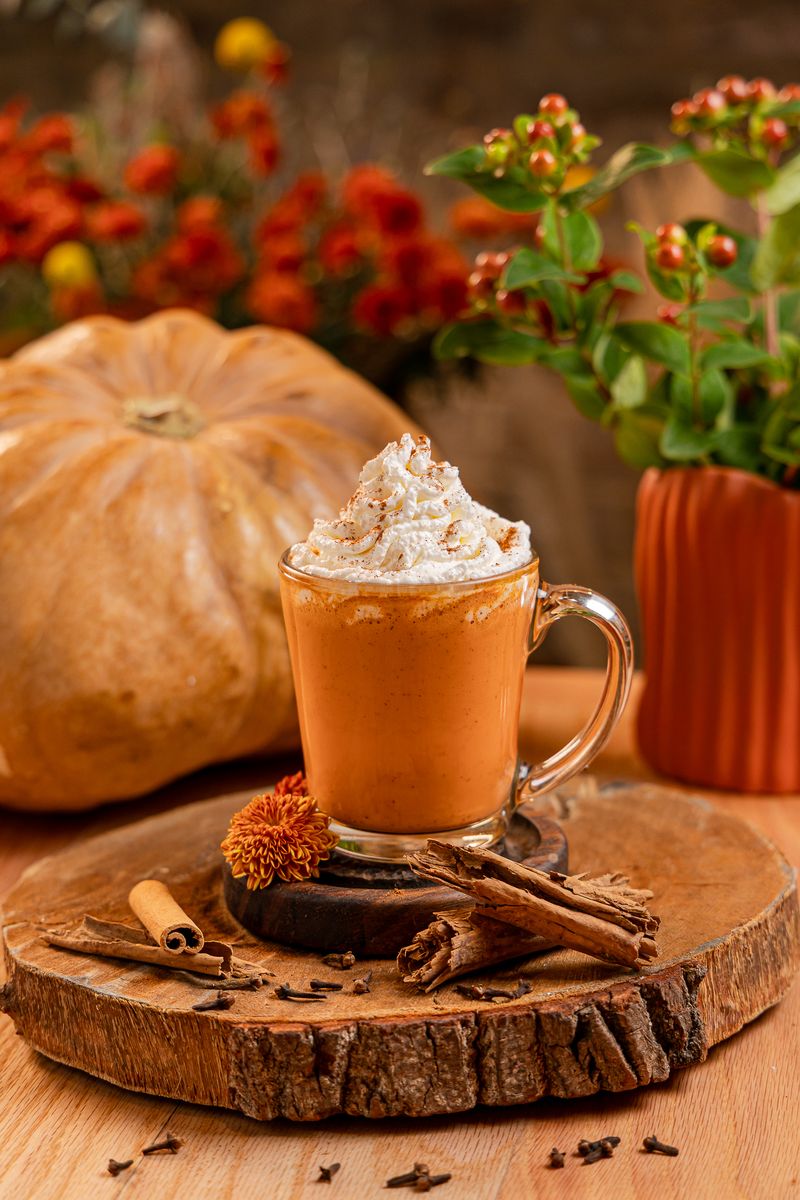 Pumpkin chai caliente con crema batida y canela frente a una calabaza