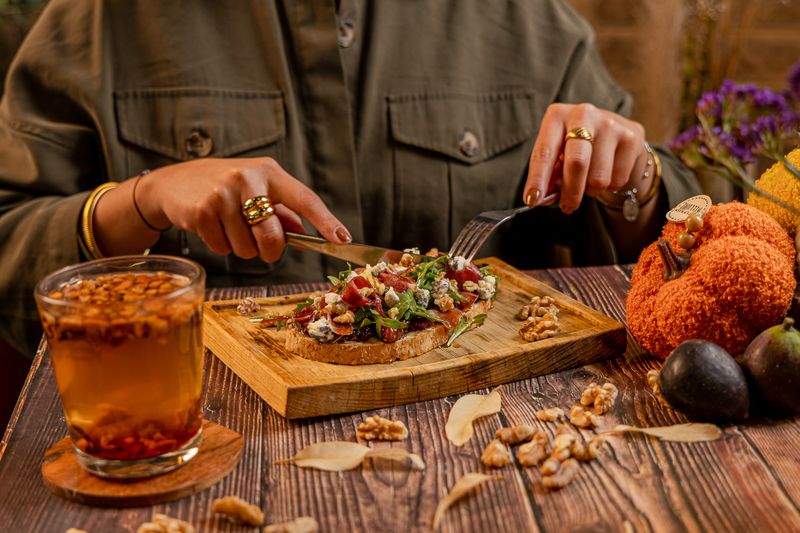 Tosta de otoño con higos, arúgula, queso de cabra y jamón serrano sobre tabla de madera
