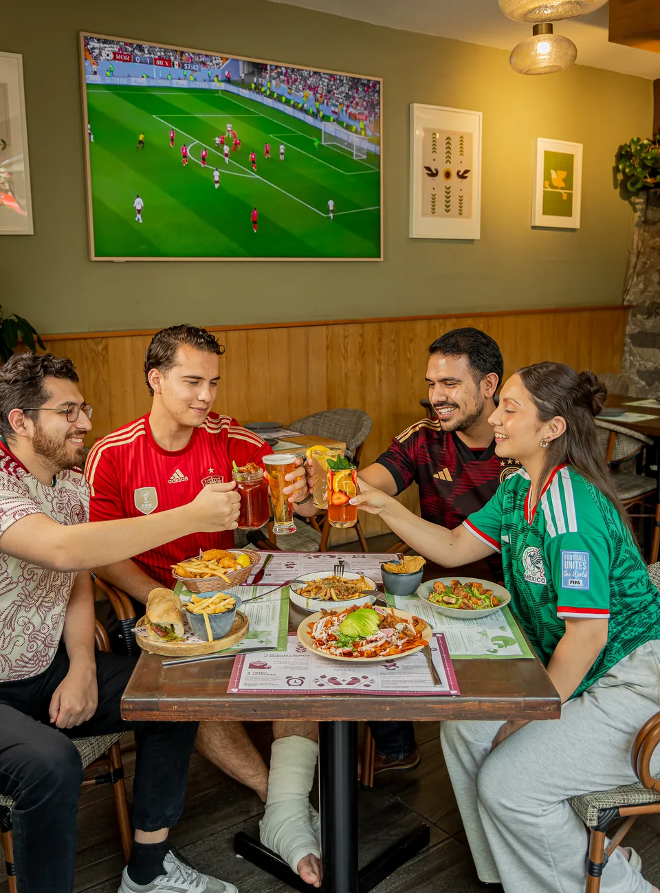 Amigos brindando y compartiendo la mesa en Tagers durante un partido