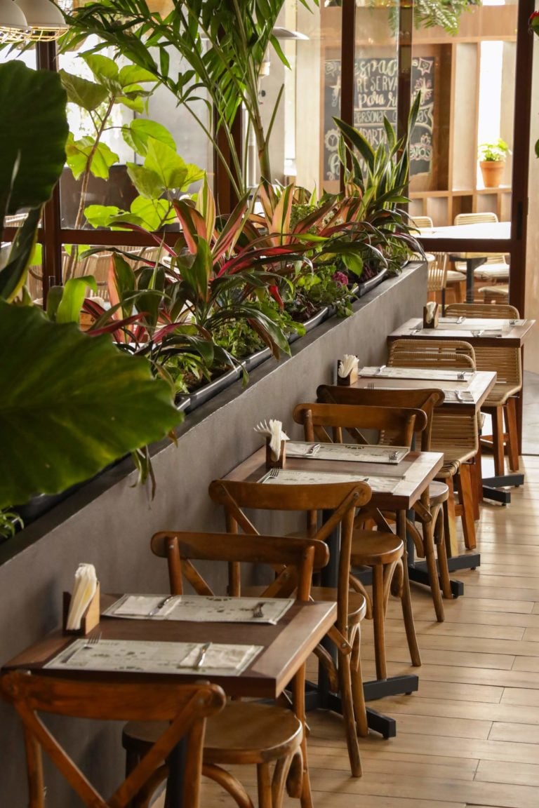 Comedor de una casa Tagers con mesas de madera y plantas