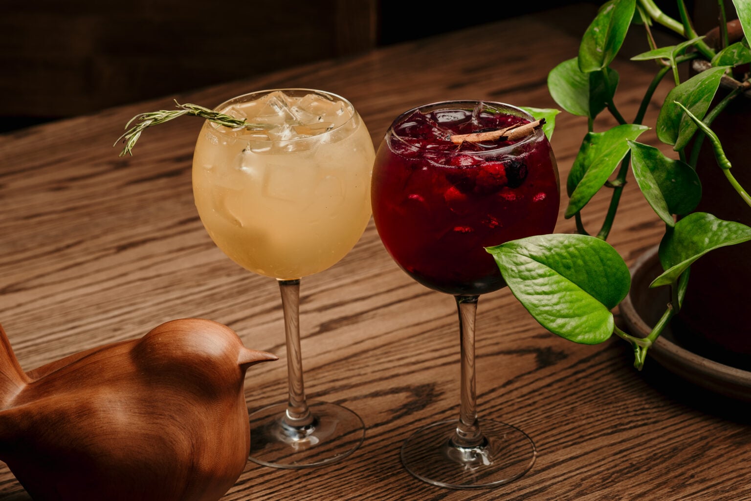 Dos bebidas de la casa junto a un pájaro de madera, en una mesa de Tagers
