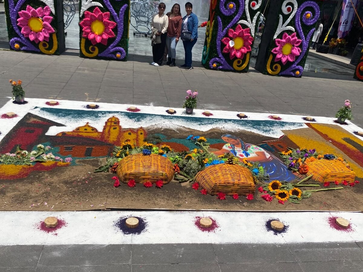 Tapete floral con paisaje de San Ángel, flores y canastas frente al arco de la Feria de las Flores 2026