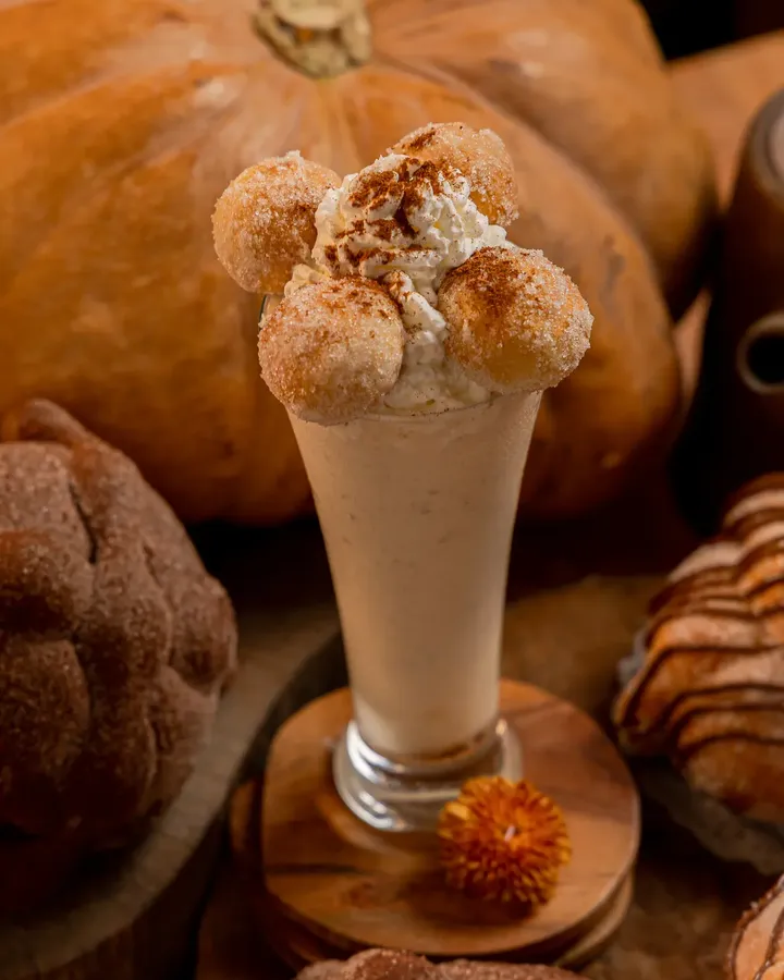 Malteada de pan de muerto de Tagers en copa alta, coronada con bolitas de pan de muerto azucarado