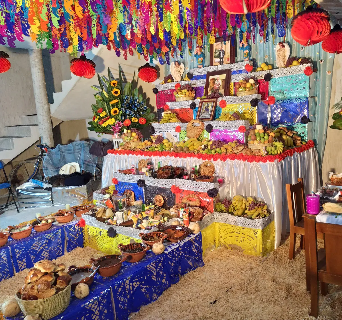Ofrenda de Día de Muertos en Puebla con papel picado, pan, fruta, flores y fotografías