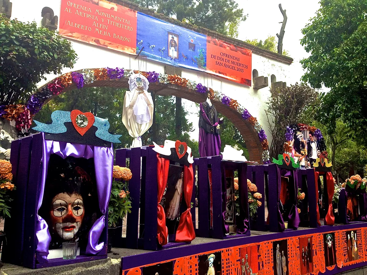 Ofrenda monumental al titiritero Alfin, con teatrinos, marionetas, un arco de flores y papel picado, bajo la manta de las Ofrendas de Día de Muertos San Ángel 2013