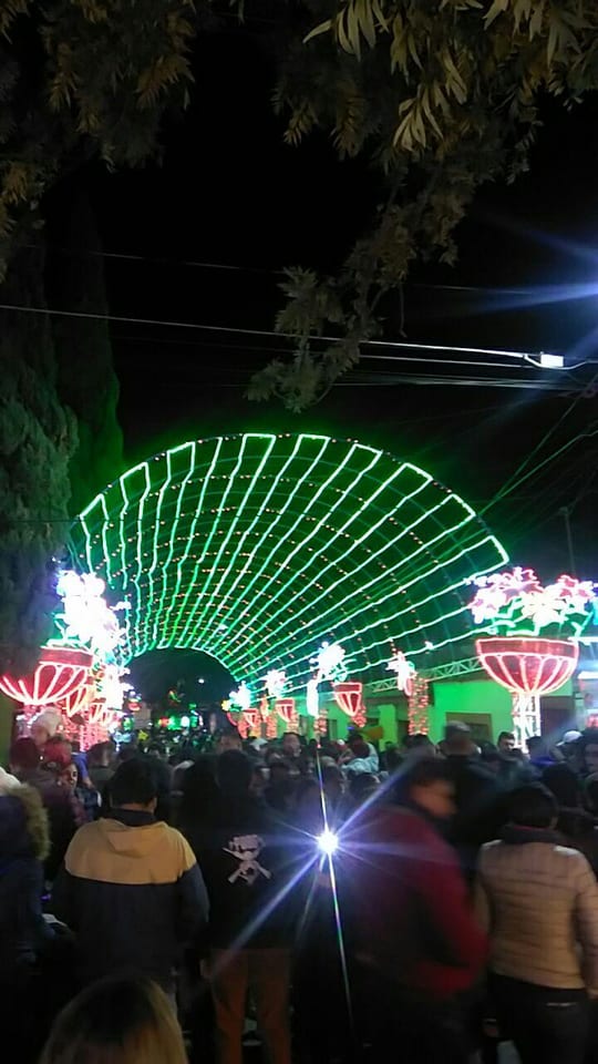 Túnel de arcos de luz verde con flores de luz y gente paseando en la Villa Iluminada de Atlixco, enero de 2020