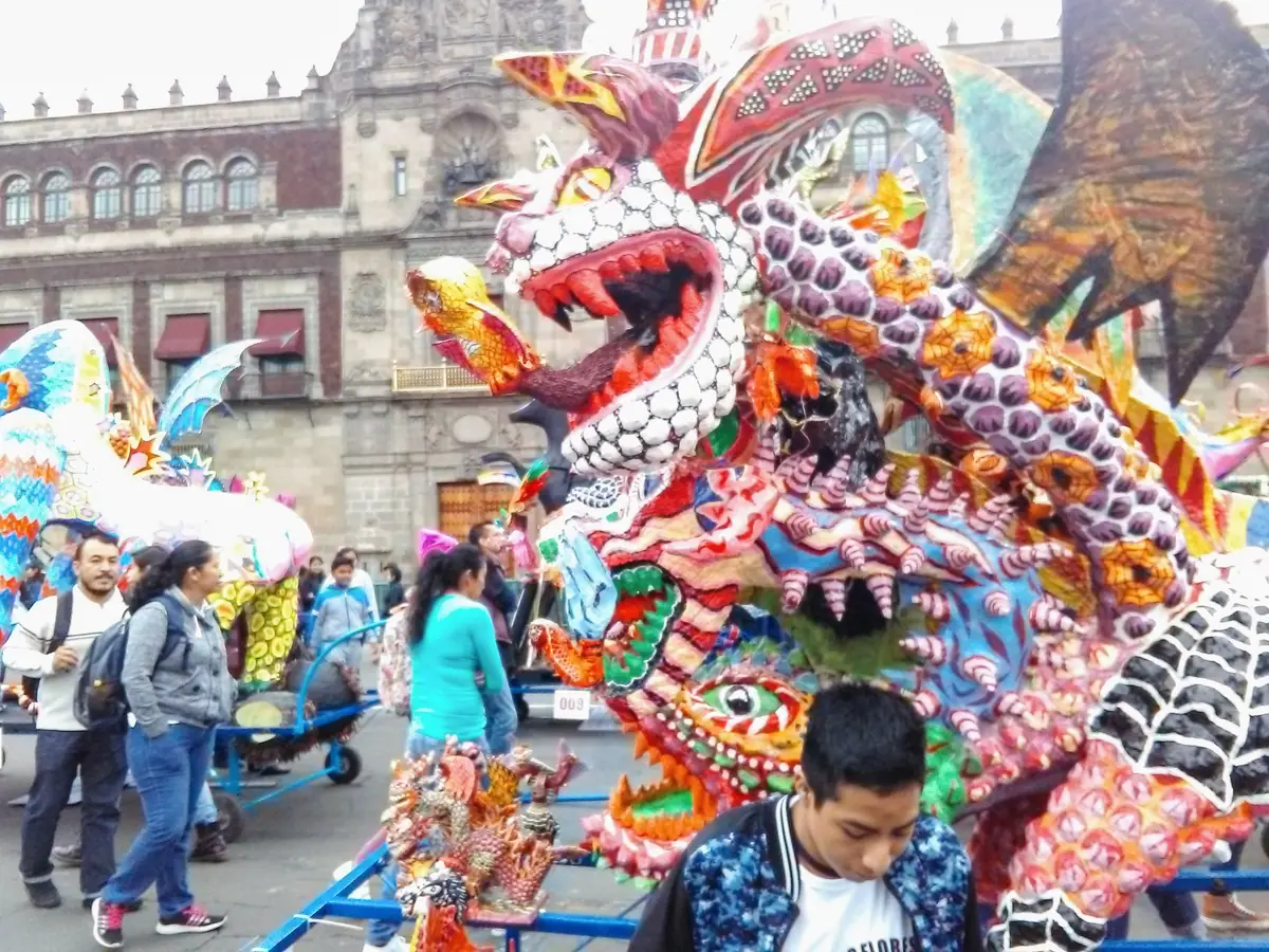 Alebrijes monumentales instalados en la plancha del Zócalo antes del desfile, con público y el Palacio Nacional al fondo
