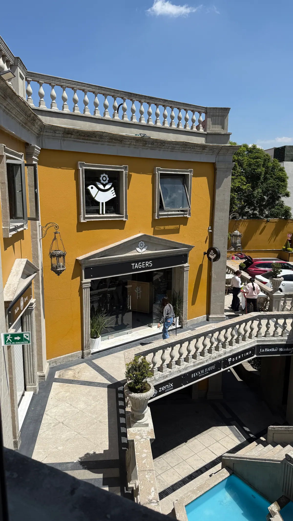 El patio de La Paz 40 en un día de sol, con la fachada amarilla de Tagers San Ángel, su letrero y la balaustrada de piedra