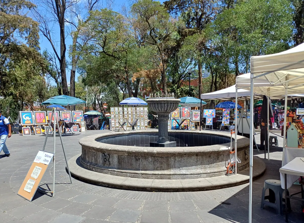 La fuente de piedra de la Plaza San Jacinto rodeada de cuadros, carpas blancas y árboles, un sábado de 2024