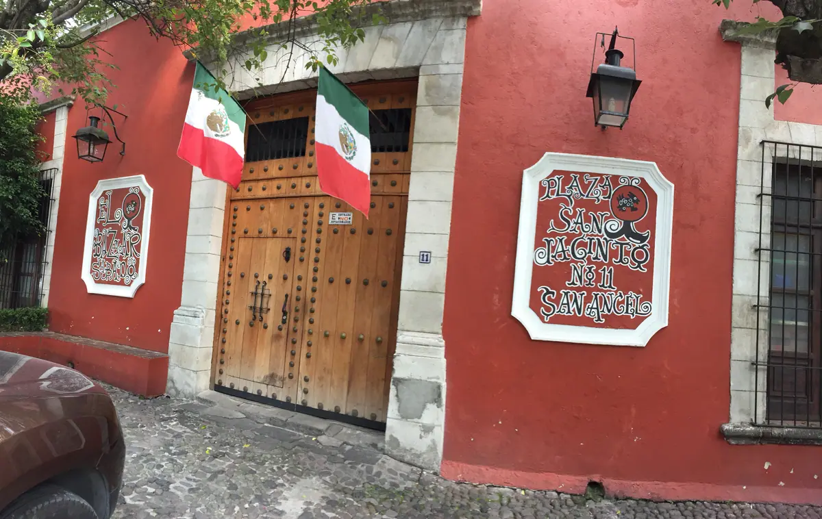 La fachada roja del Bazar del Sábado en Plaza San Jacinto 11, con su puerta de madera, dos banderas y sus letreros blancos