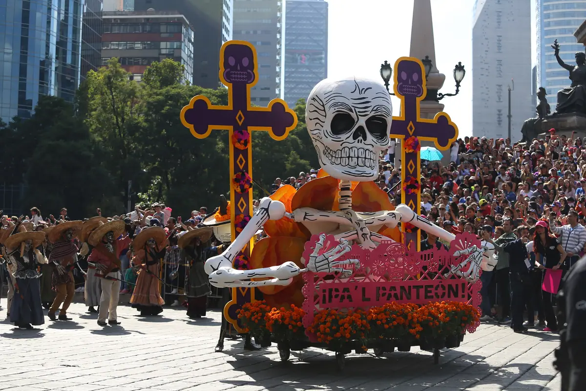 Un carro alegórico con un esqueleto pasa frente al Ángel de la Independencia, con el público apretado en las escalinatas del monumento, en el primer Gran Desfile de 2016