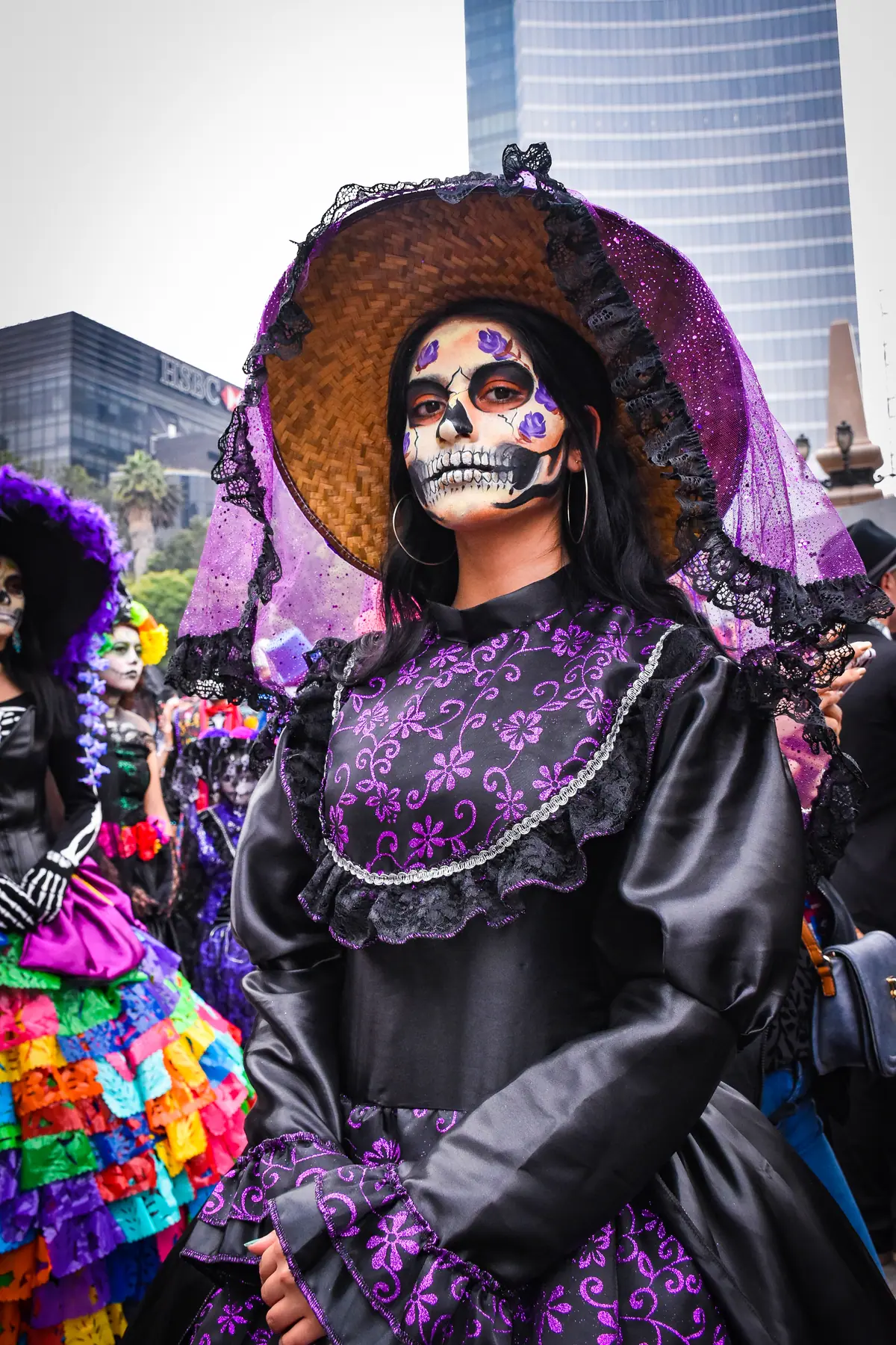 Retrato de una catrina con sombrero y velo, con un edificio de Reforma al fondo