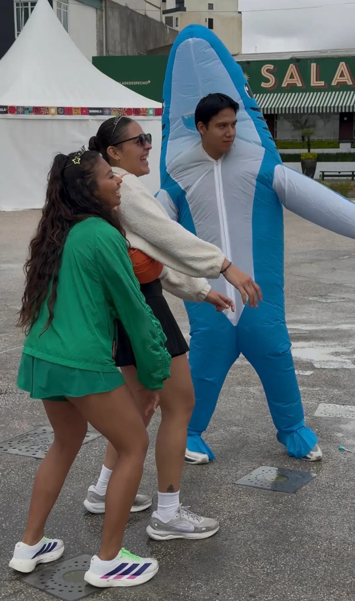 Participantes bailan junto a un disfraz inflable de tiburón