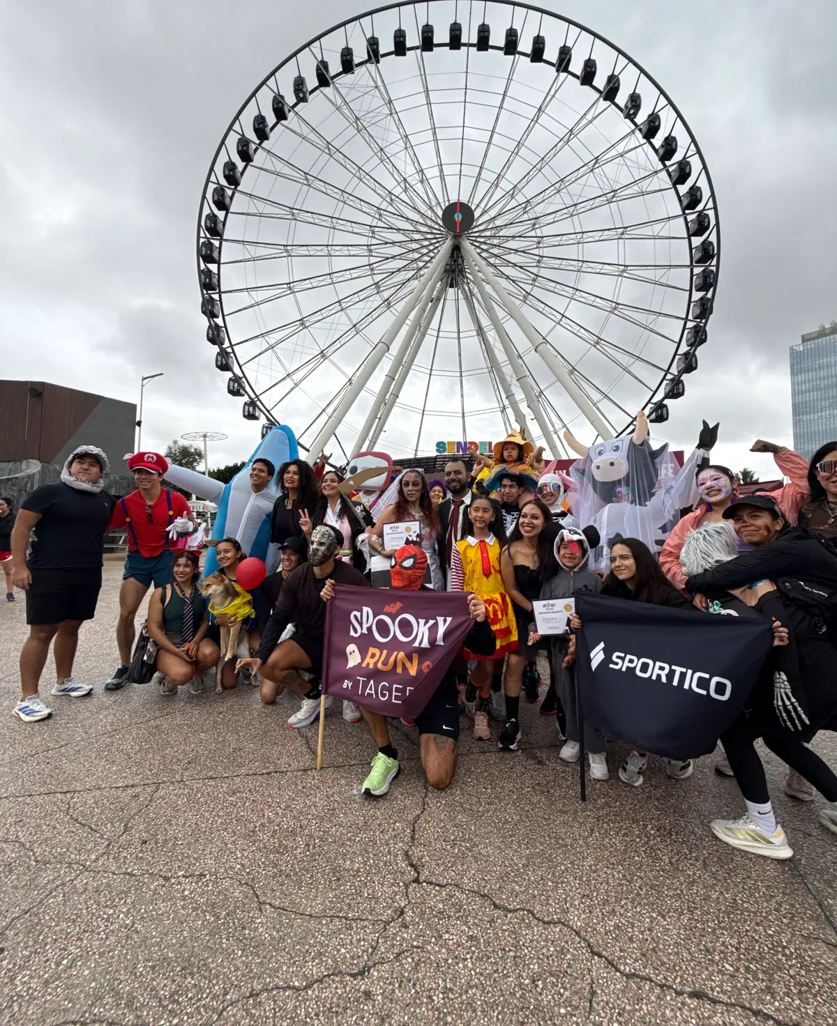 Participantes del concurso de disfraces con la bandera de la Spooky Run frente a la Estrella de Puebla