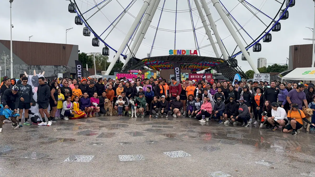 Foto grupal de la Spooky Run de Tagers frente a la Estrella de Puebla, en Sendela, con corredores disfrazados y sus perros