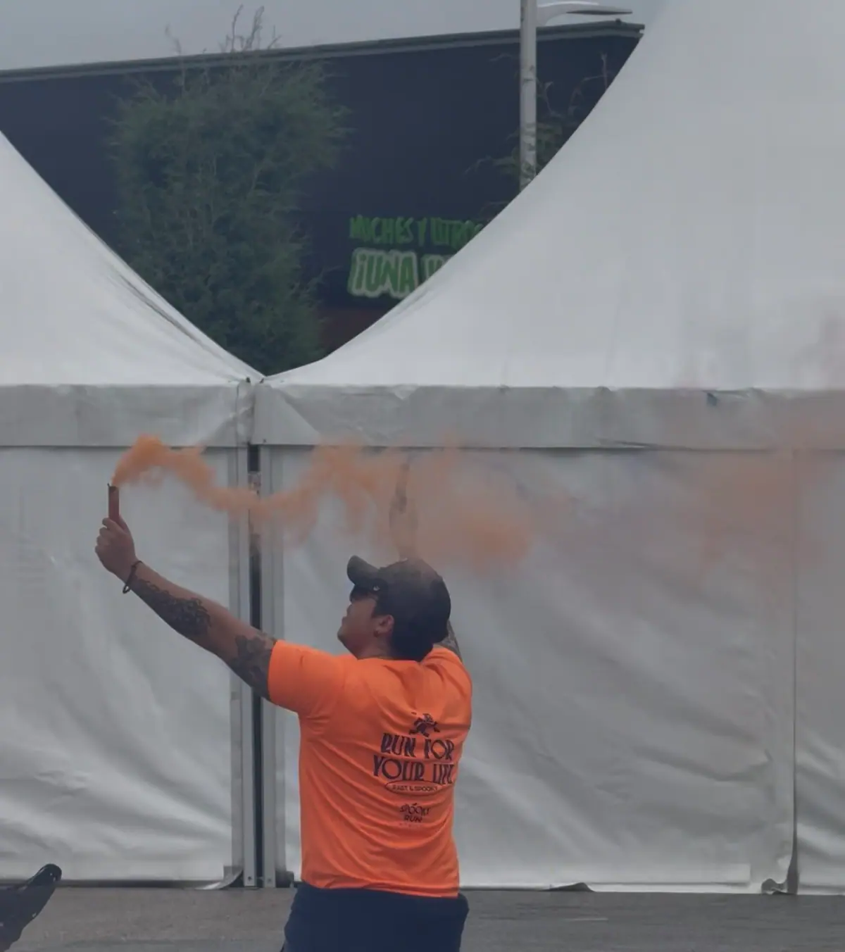 Integrante del staff con playera naranja y una bengala de humo naranja