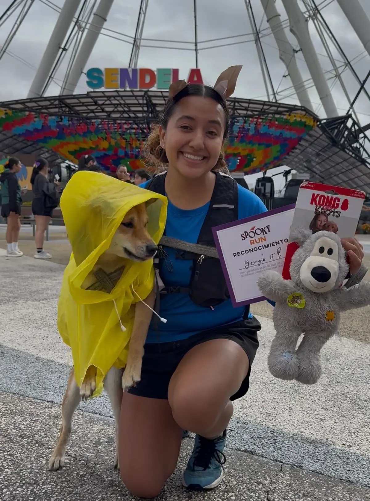Corredora con su perro de impermeable amarillo y el reconocimiento del concurso de mascotas