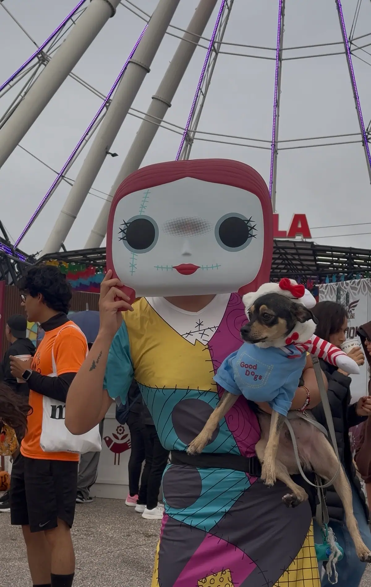 Participante con máscara de Sally, de El extraño mundo de Jack, carga a su perro disfrazado